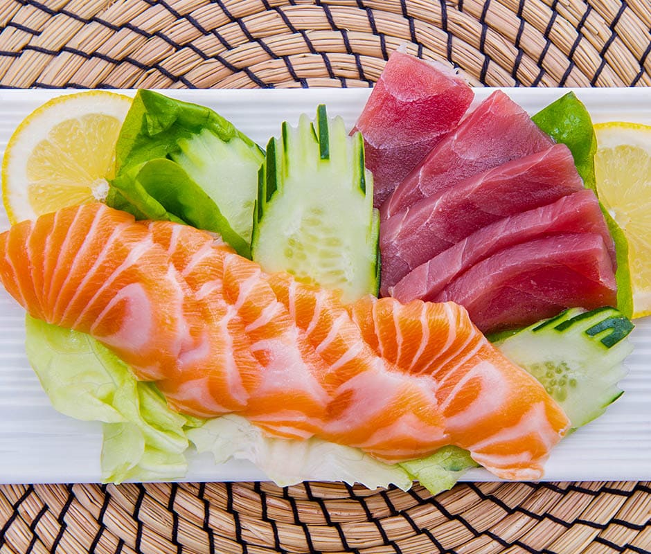 Salmon and tuna sashimi slices with cucumber and lemon garnish.